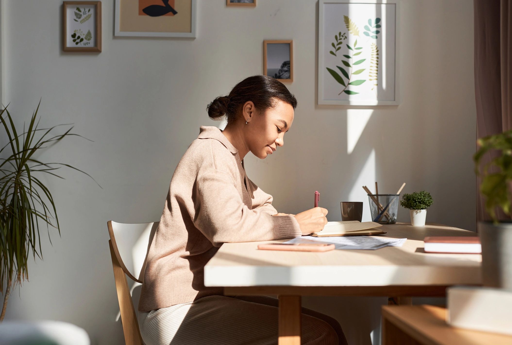 Person journaling in morning light by a window.